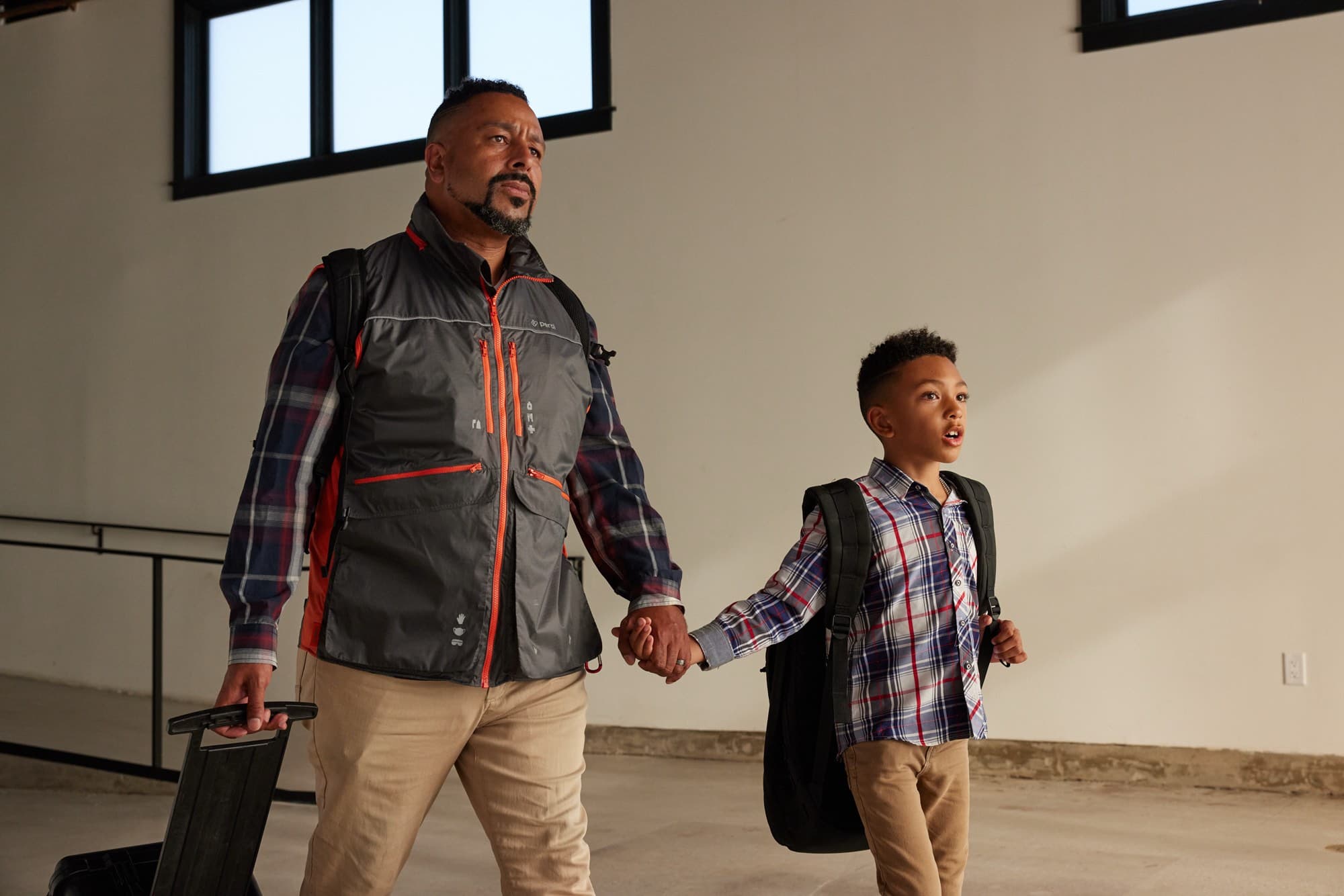 A father wearing the Perci Vest walks out holding his son's hand